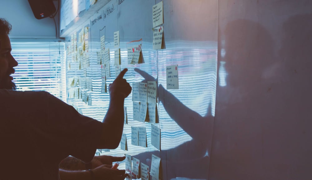 Image of people pointing to a white board